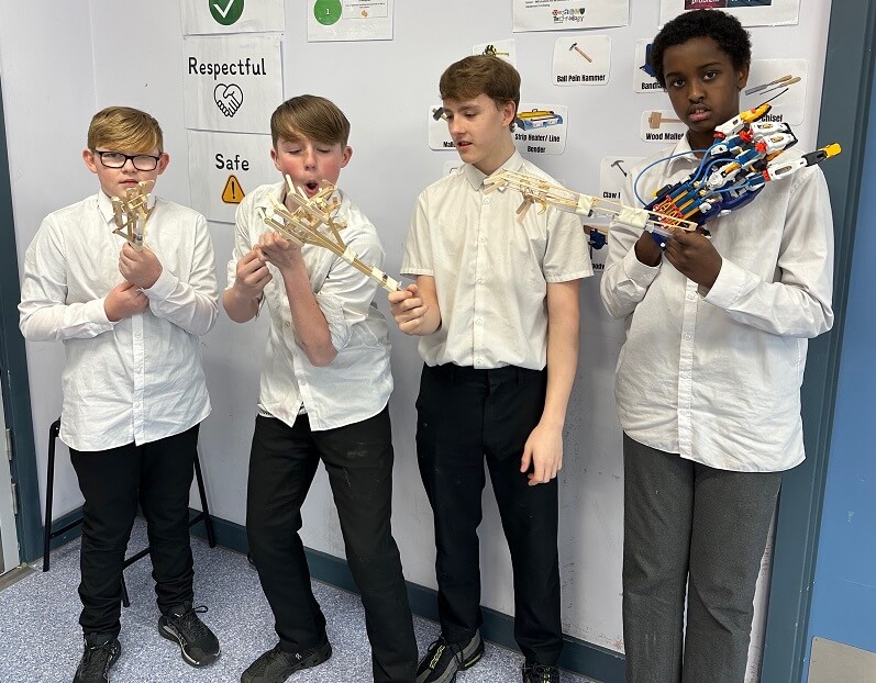 Student holding their hydraulic arm projects